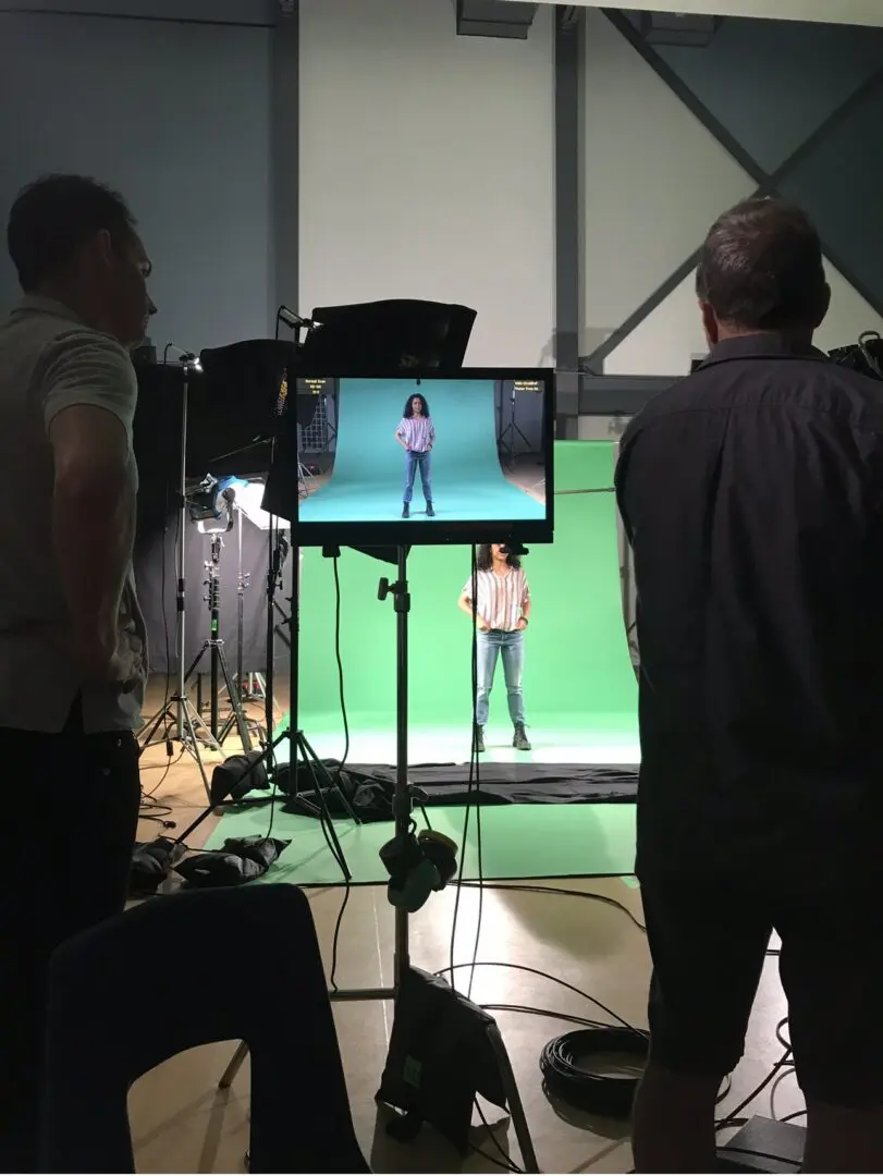 A group of people standing around in front of a green screen.