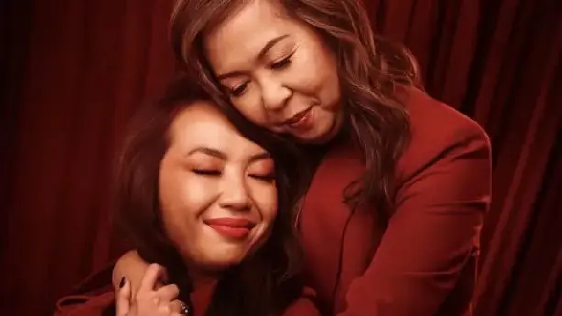 Two women are hugging and smiling for the camera.