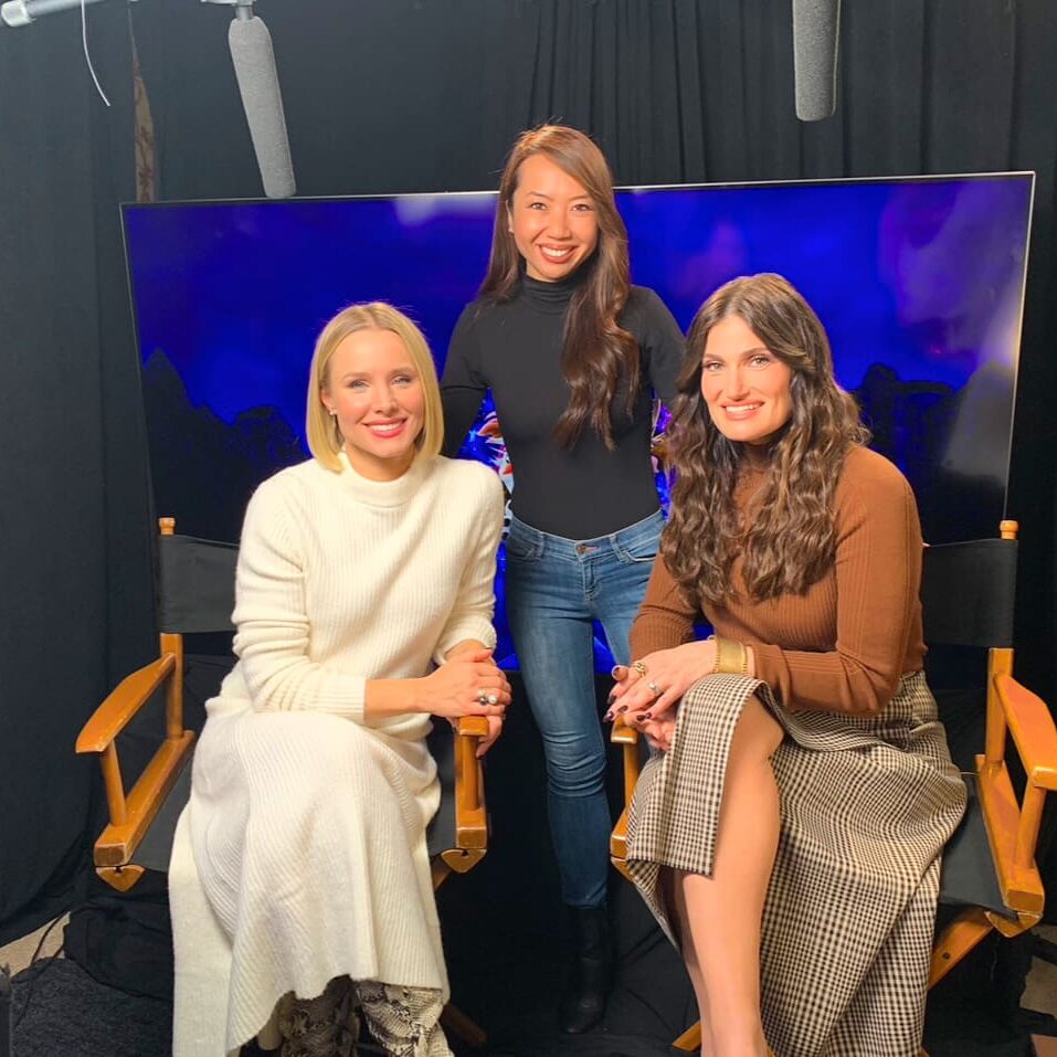 Three women sitting on a chair in front of a blue screen.