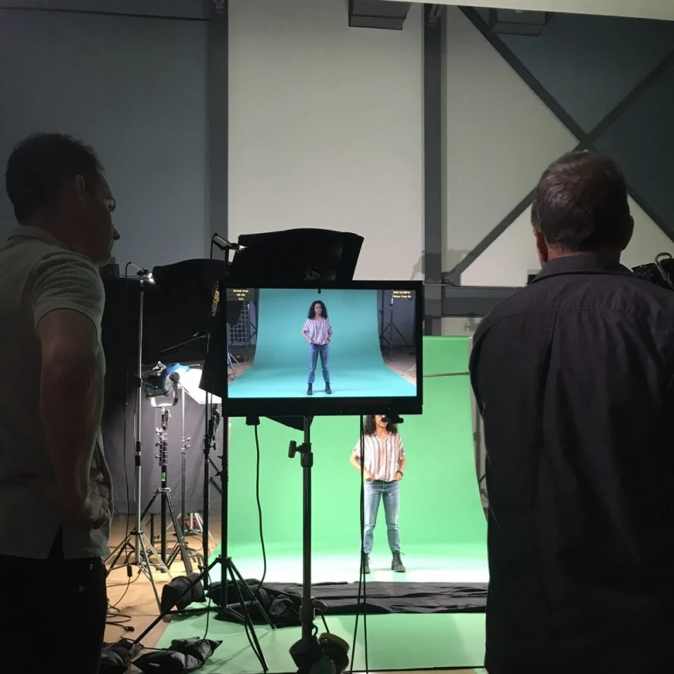 A group of people standing around in front of a tv.