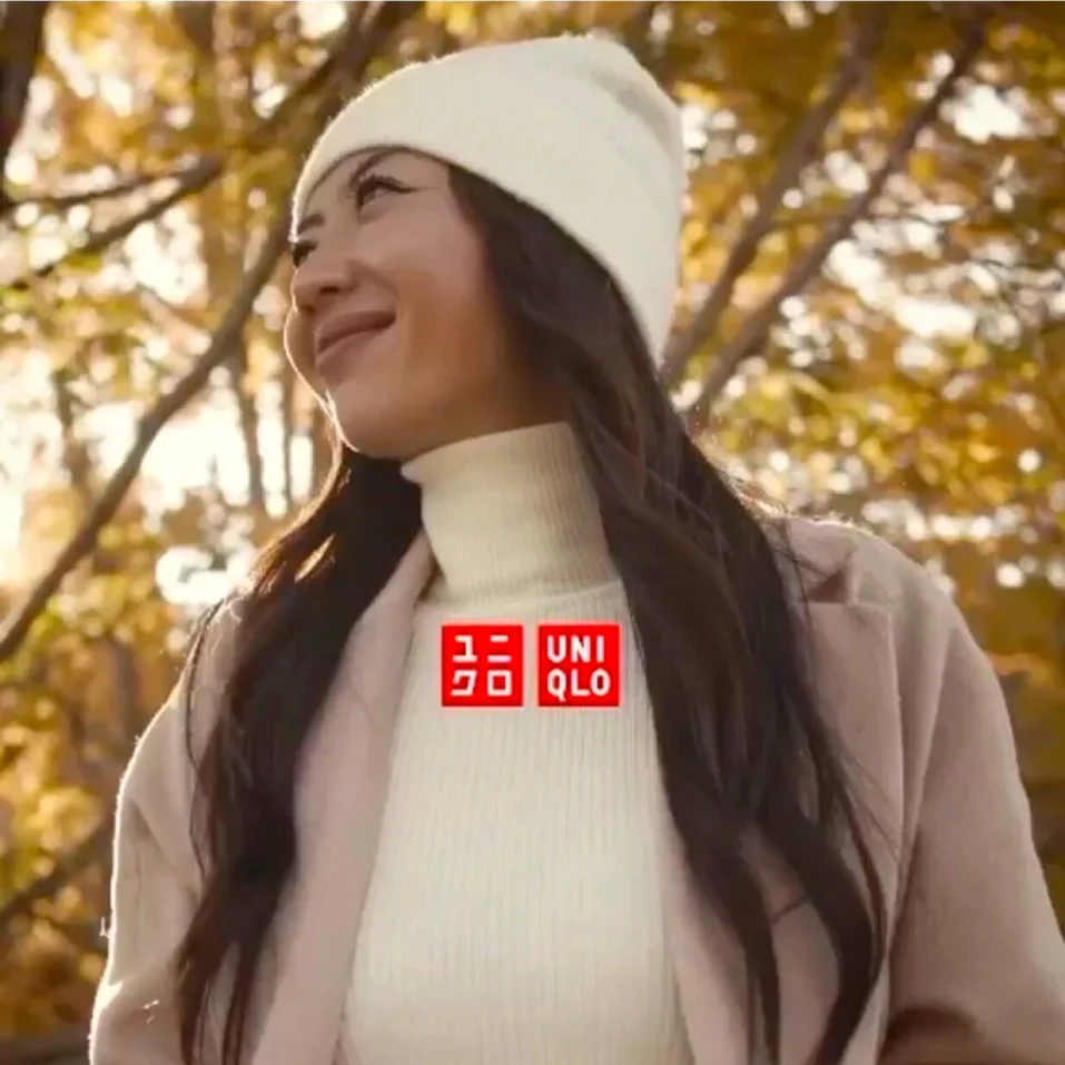 A woman wearing a hat and sweater with trees in the background.